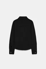 Camisa entallada color marrón oscuro, con cuello camisero y manga larga. Presenta dos bolsillos de plastrón en el delantero y cierre frontal con botones a presión dorados.