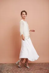 Blusa blanca con bordado de mostacillas y lentejuelas, escote redondo y manga larga.