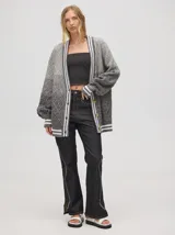 Cardigan oversize de algodón con diseño tejido a rombos en tonos degradados de marrón y blanco. Presenta cuello en V, cierre frontal con botones de madera y puños y dobladillo con rayas blancas.