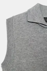 Chaleco de punto color blanco, estilo polo, sin mangas (manga sisa) y cuello solapa. La parte inferior termina en rib.