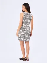 Vestido corto de línea A, color blanco con estampado geométrico en negro. Cuenta con diseño sin mangas, escote en V con cordones decorativos terminados en borlas y bolsillos laterales.
