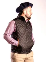 Chaleco negro capitoneado impermeable con cierre frontal y bolsillos laterales con ribete color cuero.