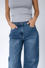 Pantalón de jean con corte balloon fit, de tiro alto y diseño holgado en las piernas. Confeccionado en denim con elastano, presenta un lavado azul clásico y cierre frontal con botón y cremallera.