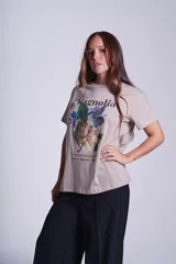 Remera blanca de algodón con estampado de flores de magnolia y texto en negro.
