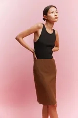 Pollera ajustada de punto color marrón, con tiro alto y elástico oculto en la cintura. Modelo a la rodilla con costuras visibles en el frente y tajo en la parte trasera.