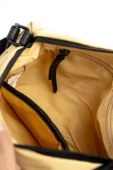 Bandolera Mishka color beige confeccionada en nylon, con correa negra ajustable de poliéster. Cuenta con cierre superior y el logo estampado en el frente.