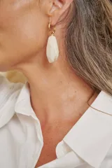 Aros colgantes dorados con dije de piedra acrílica color arena de forma facetada.