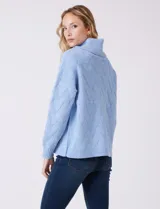 Buzo de punto grueso con textura en relieve, de cuello volcado y mangas largas con hombros caídos. Presenta puños y ruedo con terminación en rib.