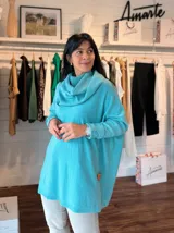 Polerón oversize de tejido de punto en color fucsia, con cuello alto tipo polera, mangas largas con puños acanalados y diseño holgado. Presenta un aplique decorativo en cuero en la parte inferior.
