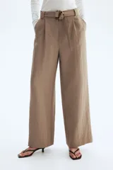Pantalón de tiro alto con corte holgado y piernas amplias, color marrón, con pliegues delanteros y cinturón del mismo tejido con hebilla circular.