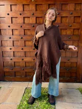 Ruana tejida en color chocolate, confeccionada en lana, con diseño de textura lisa y terminaciones con flecos largos en los extremos.