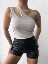 Top negro brillante de un solo hombro con abertura en el hombro izquierdo.