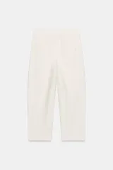 Pantalón de tiro medio en color crudo, con diseño de corte recto y trabillas en la cintura. Presenta cierre frontal con cremallera y gancho metálico.