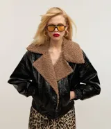 Campera biker negra de cuero sintético con efecto barnizado y cuello de peluche marrón. Tiene cierre delantero cruzado, mangas largas con puños ajustados y bolsillos laterales.