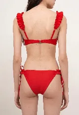 Conjunto de bikini color rojo, compuesto por un corpiño con aros y volados en los breteles, y una bombacha con volados laterales y tiritas ajustables.
