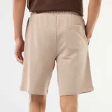 Bermuda de felpa ligera en color beige, con cintura elastizada y bolsillos laterales.