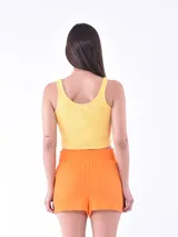 Musculosa corta de tejido acanalado color verde menta, con escote redondo y tirantes anchos. Presenta un pequeño bordado frontal con forma de flor o mariposa en tonos rosados.