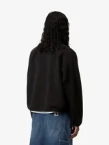 Campera de polar negro con textura de borreguito, cierre frontal con botones a presión y paneles de nylon contrastantes en el pecho. Cuenta con bolsillos laterales con cierre y el logo de la marca aplicado en el pecho.