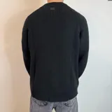 Sweater verde oliva de tejido grueso con cuello alto y mangas raglán. Corte holgado.