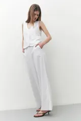Pantalón blanco de lino, de corte ancho y con tajo lateral en el ruedo.