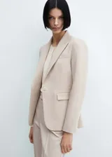 Blazer entallado de color beige con solapas de muesca, hombros estructurados y cierre frontal de un botón. Presenta bolsillos de ribete delanteros, pinzas de entalle y abertura posterior.