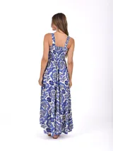 Vestido largo de corte holgado con estampado floral en tonos azul y blanco. Presenta escote cuadrado, cuerpo con frunces elásticos y falda con volados escalonados.