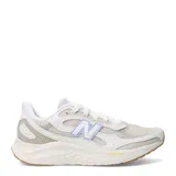 Championes de running New Balance modelo Fresh Foam Arishi v4, en tonos beige y blanco con detalles en lila. Presentan capellada de mesh respirable con refuerzos sintéticos, mediasuela con tecnología Fresh Foam para amortiguación y suela de goma color caramelo.