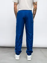 Pantalón deportivo negro de nylon con detalles en contraste blanco y logo de Umbro bordado en el lateral. Corte relajado.