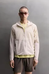 Chaqueta cortavientos de Zara Athleticz color beige, de tejido técnico ligero y elástico, con cuello subido, capucha, cierre frontal de cremallera y bolsillos laterales con cierre oculto.