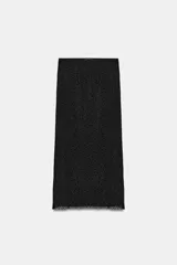 Falda midi confeccionada en tejido semitransparente negro con patrón de lunares flocados, tiro medio y cintura elástica. Cuenta con forro interior combinado a tono.