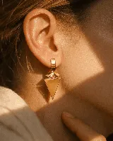 Aros colgantes de diseño geométrico en color dorado, compuestos por una pieza superior rectangular y un dije triangular invertido con una pieza intermedia semicircular.