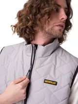 Chaleco acolchado Caterpillar color gris, con diseño de costuras en chevrón, cuello alto, cierre frontal y bolsillos laterales con cierre. Incluye parche con el logo de la marca en el pecho.