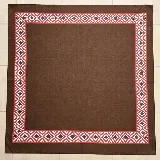 Pañuelo de seda marrón con un borde estampado geométrico en tonos rojos, blancos y negros.