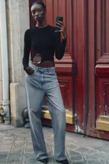 Top corto y ajustado de punto canalé color negro, con cuello redondo, manga larga y detalle de aplique metálico en la parte delantera.