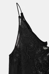 Top negro de viscosa con escote pico y tirantes finos. Presenta un aplique de encaje negro con diseño ornamental en el centro del pecho.