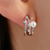 Aros dorados con forma de argolla triple, con incrustaciones de strass y una perla.
