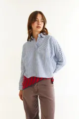 Camisa de corte oversize y estilo casual, confeccionada en algodón negro con costuras a contratono en color blanco. Presenta cuello camisero, cierre frontal parcial, mangas largas y un bordado distintivo en el puño.