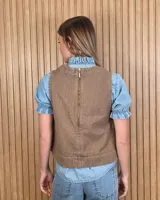 Chaleco marrón de denim con pespuntes en contraste, cuello redondo y cierre frontal con botones.