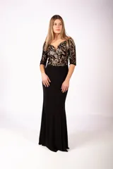 Vestido largo de fiesta con falda negra lisa y cuerpo superior de encaje con diseño floral y lentejuelas, escote en V y mangas tres cuartos.