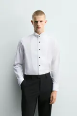 Camisa slim fit de algodón con cuello smoking, manga larga con puño doble para gemelos y pechera combinada a tono con cierre frontal de botones.