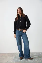 Cardigan de punto negro con cuello camisero, cierre frontal de botones y mangas largas con puños acanalados.