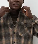 Camisa de manga larga confeccionada en franela de algodón, con diseño de cuadros, cuello inglés, cierre frontal con botones y un bolsillo en el pecho.