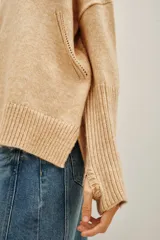 Polera de cuello alto en color beige, confeccionada en tejido de punto suave. Presenta un diseño clásico de manga larga con puños acanalados.