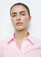 Camisa entallada de popelín de algodón color rosado, con cuello camisero, manga larga y cierre frontal oculto con botones bajo tapeta.