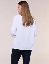 Blusa blanca de silueta holgada confeccionada en tejido texturizado con escote bote y mangas tres cuartos abullonadas con detalles de broderie calado.