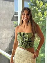 Top strapless de satén color verde oliva, con diseño de nudo frontal drapeado y estructura ajustada.