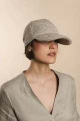 Gorra con visera confeccionada en lana fina sin teñir, con un sutil patrón de tejido en espiga.
