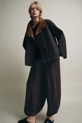 Pantalón de tiro medio con cintura elástica ajustable y cordón de ajuste. Diseño holgado con patrón de cuadros pequeños en tonos marrón oscuro y negro. Los bajos terminan en puño elástico.