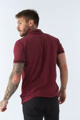 Polo gris de piqué de algodón, corte regular, manga corta con ribete azul marino, cuello clásico con botones y logo bordado en el pecho.