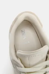 Zapatillas deportivas estilo barefoot confeccionadas en una combinación de piel vacuno y ante. Presentan un diseño de puntera amplia para mayor libertad de movimiento, suela plana y flexible con efecto engomado, y cierre mediante cordones. Incluyen detalles de pespuntes y paneles en contraste de color en la parte trasera.